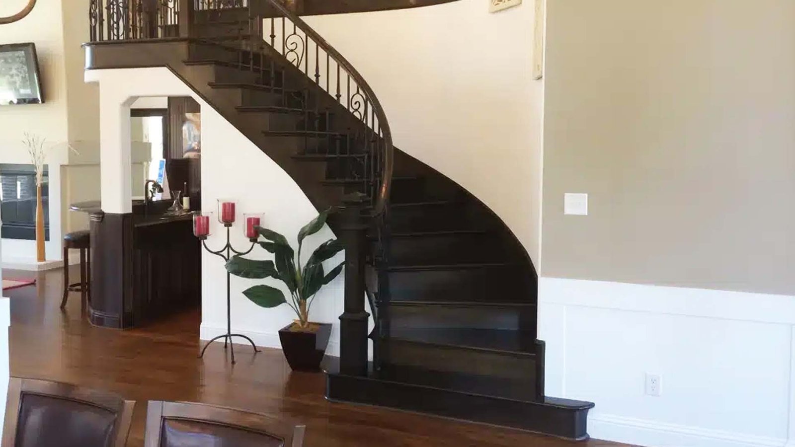 Curved staircase with dark wood treads and a wrought-iron railing above a hardwood floor